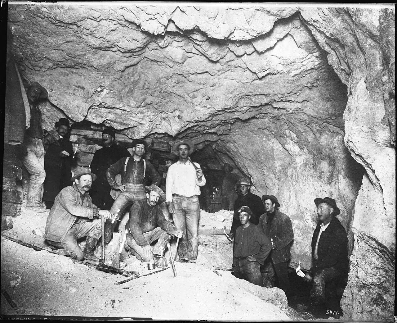 An interior view of a mine with men at work.