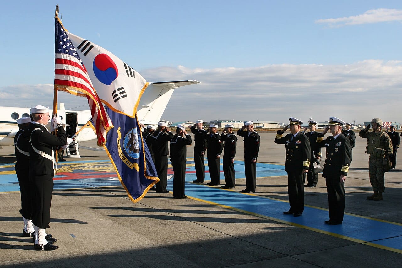 Military saluting US and SK flags