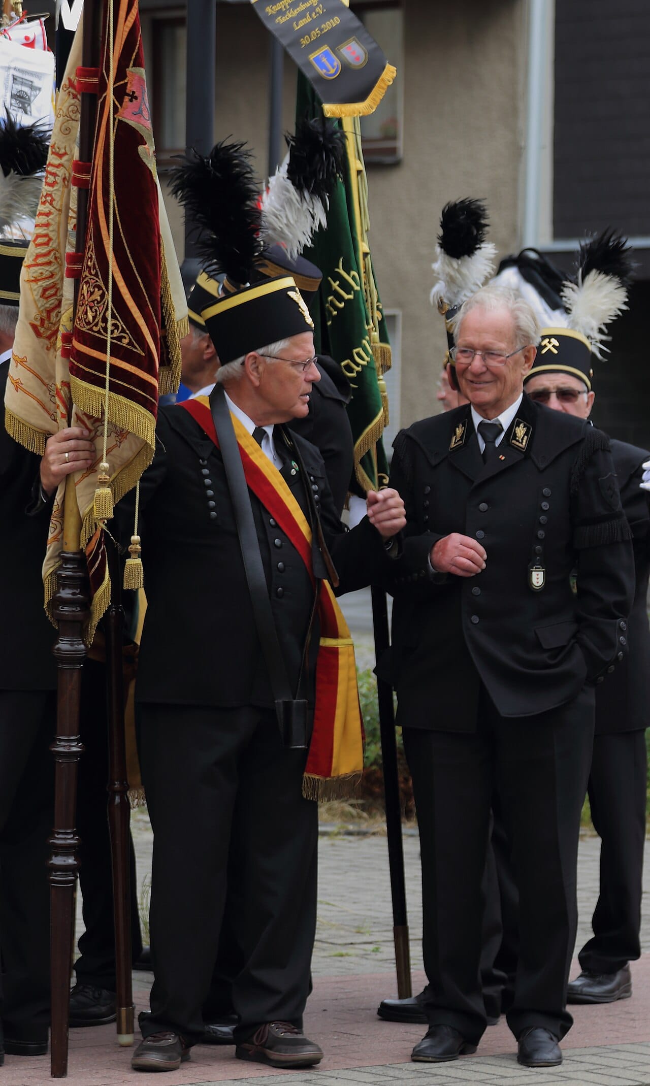 Two men in tunic and plumed shako at a mining service, 2015.
