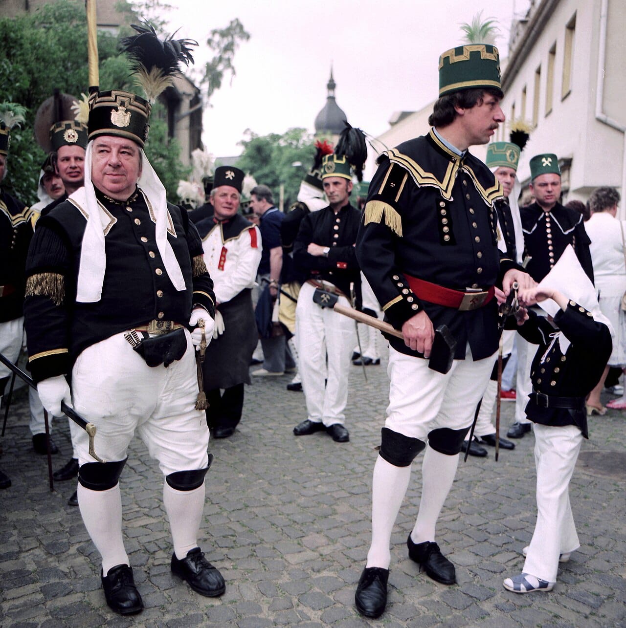 A miner in black tunic and white breeches, the leather apron behind, at a 1987 anniversary parade.