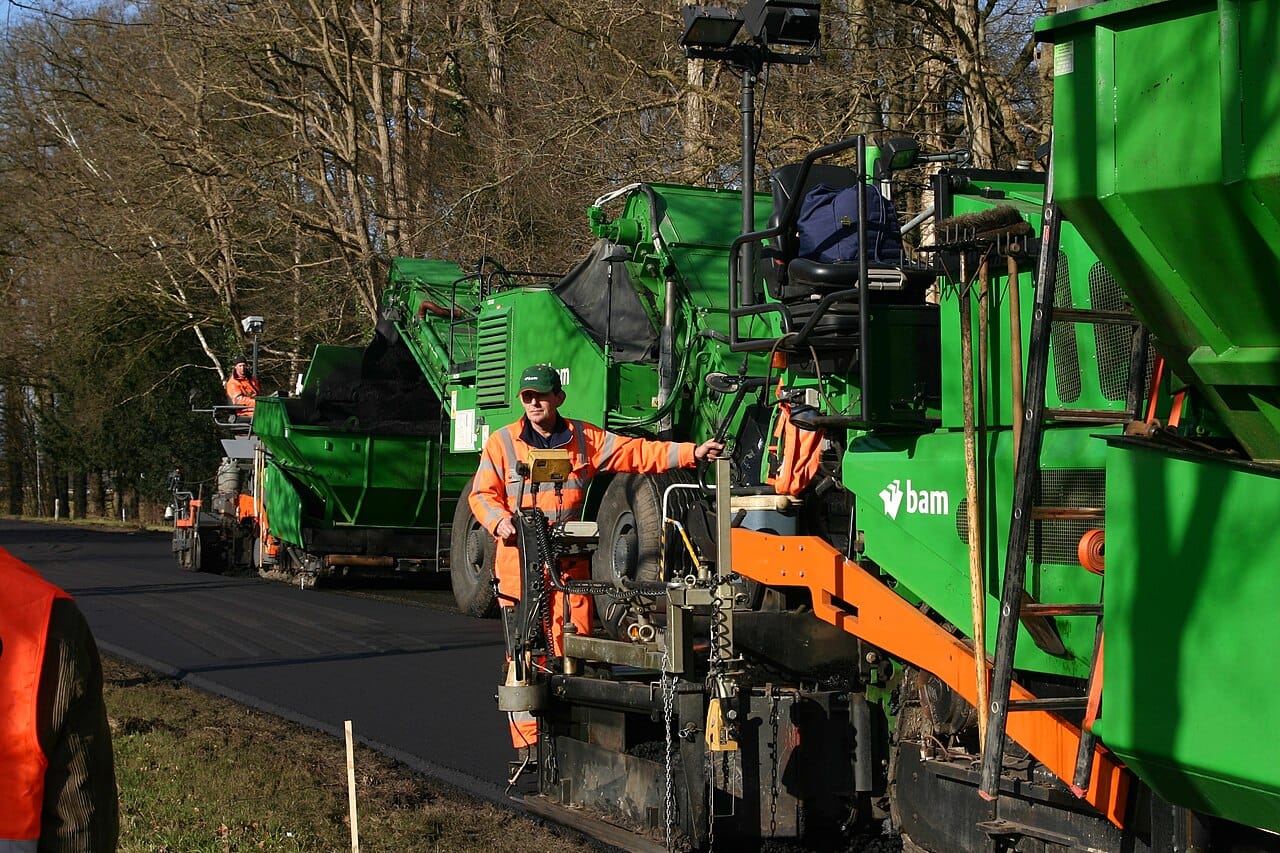 A road crew laying asphalt, in orange.