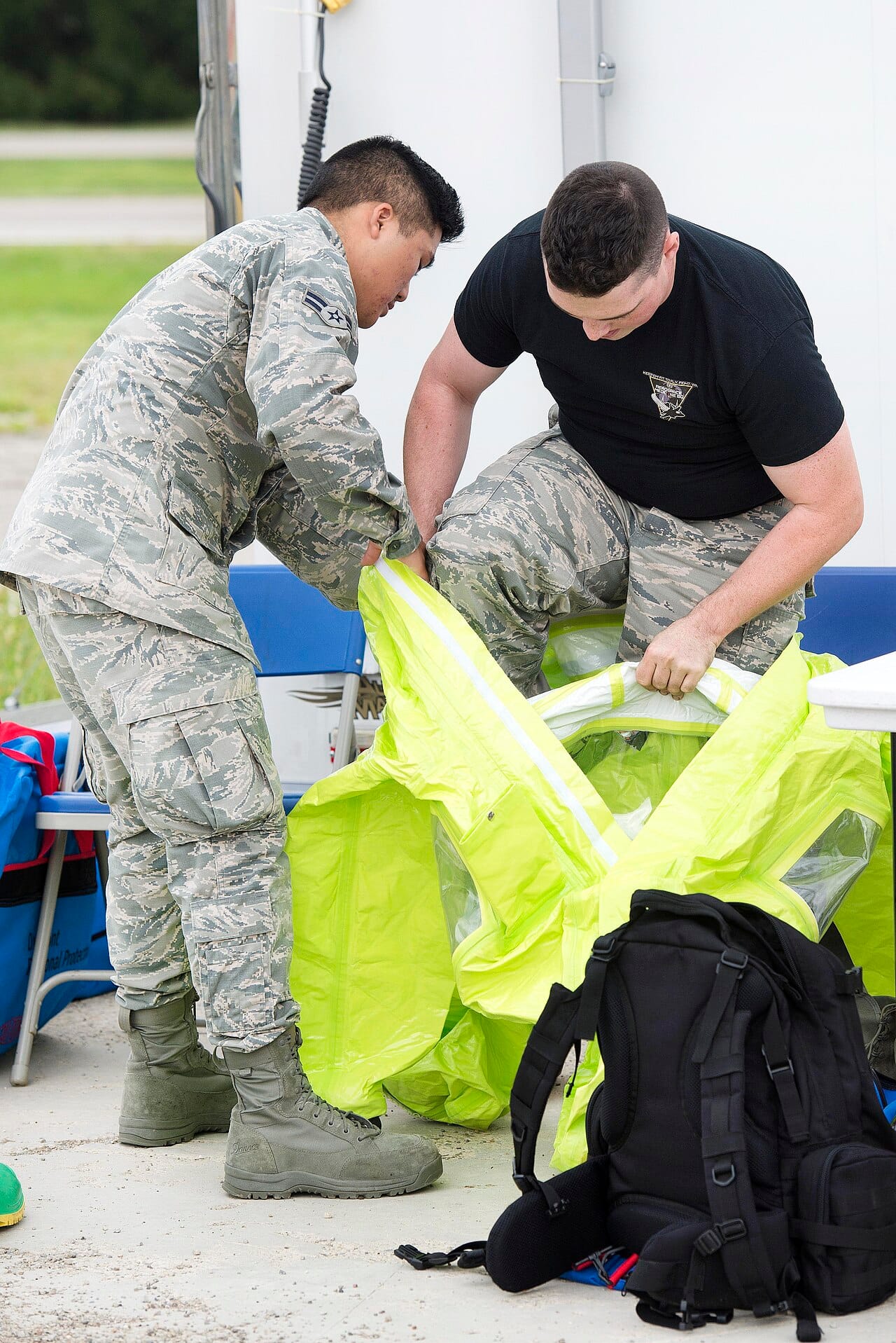 An airman pulling on a protective suit.