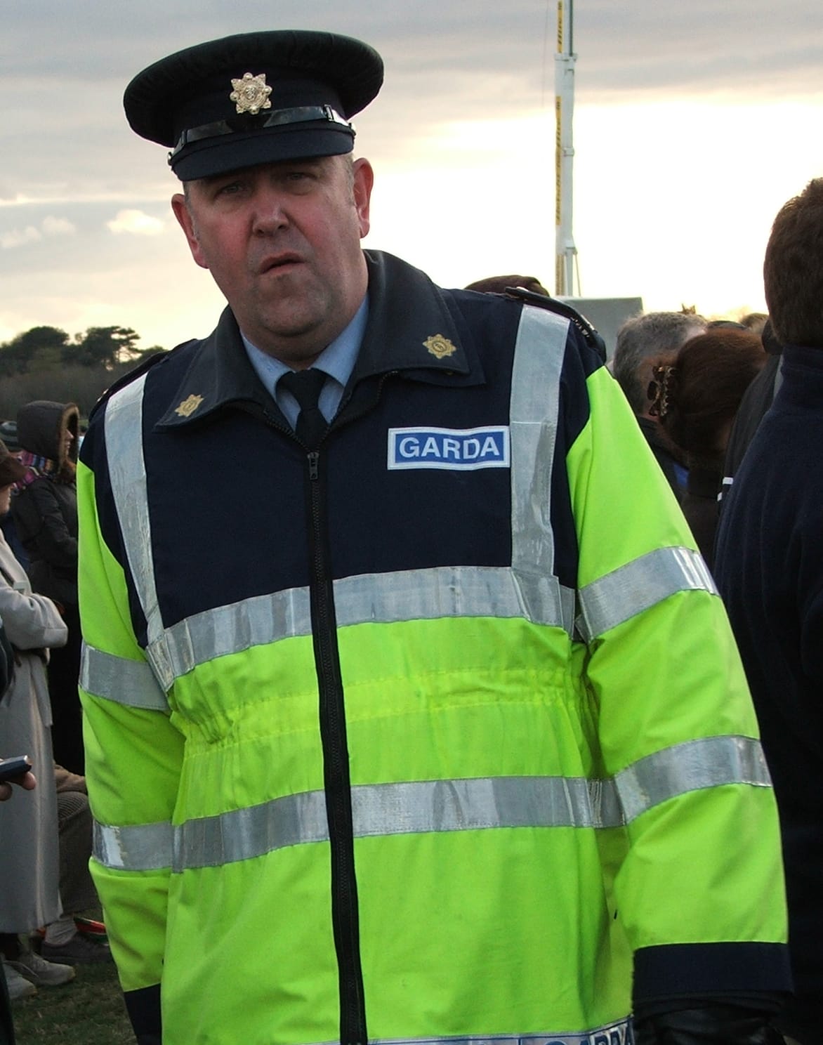 An Irish police officer in a high-visibility jacket, the force's name across the chest.