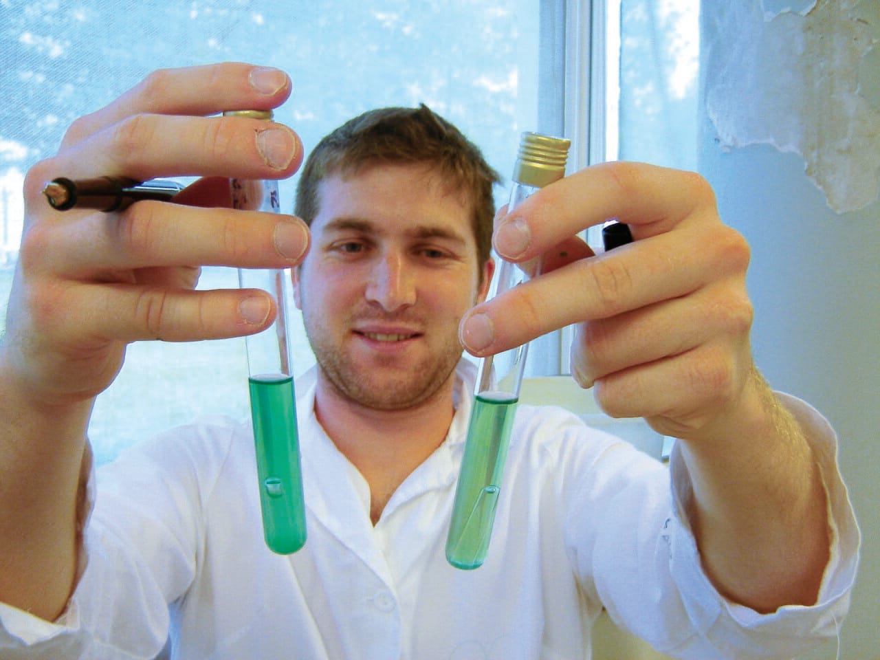 A student holding two tubes of coloured liquid to the camera.