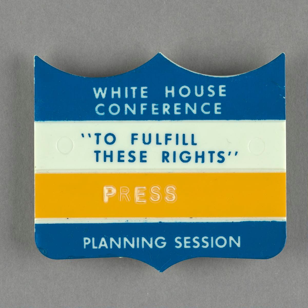 The badge front: a die-cut shield in blue and gold, reading PRESS.