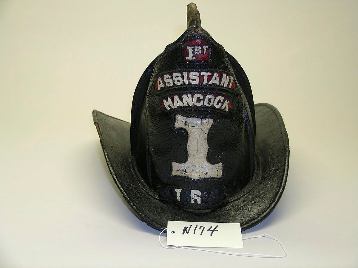 A helmet lettered "Hancock", the leather crazed and darkened across the crown.